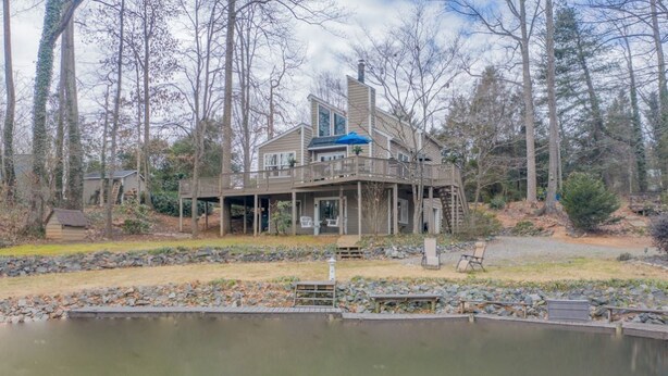 A two-story house with a deck and a pond in the foreground.