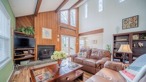 A spacious living room with a fireplace, leather sofa, wooden coffee table, and a television.