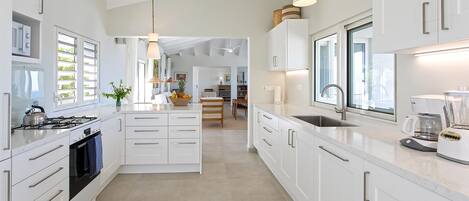 Una cocina moderna con armarios blancos, estufa a gas y cafetera.