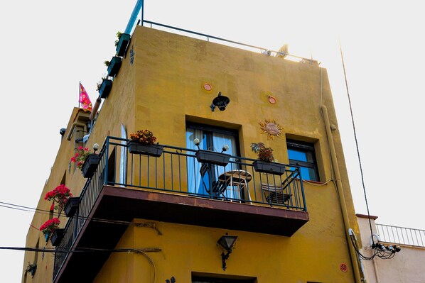 A yellow building with a balcony, a window, and a door.