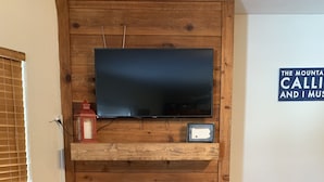 Una sala de estar con una pared de madera, un televisor de pantalla plana montado sobre la chimenea y un cartel en la pared.