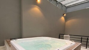 A hot tub with a wooden surround, a metal roof, and two wall-mounted lights. - Hotel Traful (Mar del Plata)