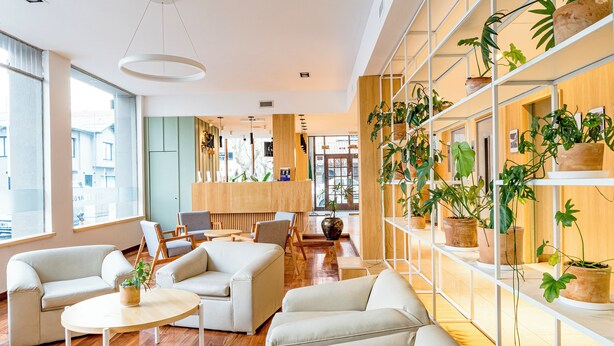 A modern interior with sofas, a round table, and a plant wall. - Hotel Traful (Mar del Plata)
