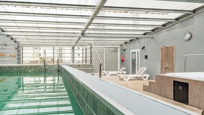 An indoor swimming pool with clear lanes, a changing room with showers, and a clock on the wall. - Hotel Traful (Mar del Plata)