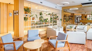 A modern interior with wooden floors, blue and white furniture, and a plant-filled wall. - Hotel Traful (Mar del Plata)