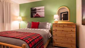 A bedroom with a bed, a dresser, two lamps, a mirror, and a painting on the wall. - Apex Mountain ~ Beaconsfield Getaway (Apex Mountain Resort)