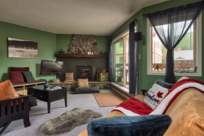 Un salon chaleureux avec une cheminée en pierre, un téléviseur et un canapé confortable.