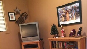 A room with a bed, a television, a bookshelf, and a small Christmas tree. - Apex Mountain ~ Moose Lodge (Apex Mountain Resort)