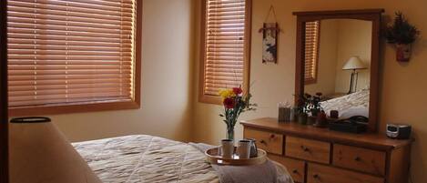 A bedroom with a bed, dresser, mirror, and a lamp.