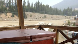 A wooden deck with a hot tub, a barbecue grill, and a small table. - Apex Mountain ~ Moose Lodge (Apex Mountain Resort)