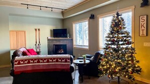 Una sala de estar acogedora con chimenea, un árbol de Navidad y un sofá con una manta festiva.