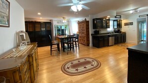 Uma cozinha ampla com armários de madeira, um espaço de refeições com mesa e cadeiras, e um ventilador de teto.