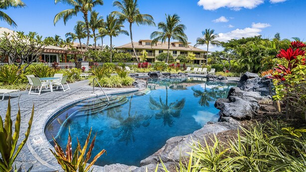 Ein Resort mit Schwimmbad, Palmen und einem Gebäude mit Balkonen.