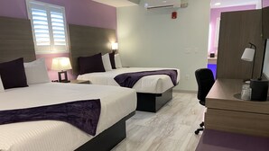 Habitación de hotel con dos camas, un escritorio, una silla, una lámpara y una ventana con persianas.