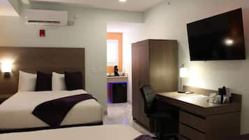 Een hotelkamer met twee bedden, een bureau, een stoel, een televisie en een airconditioning.