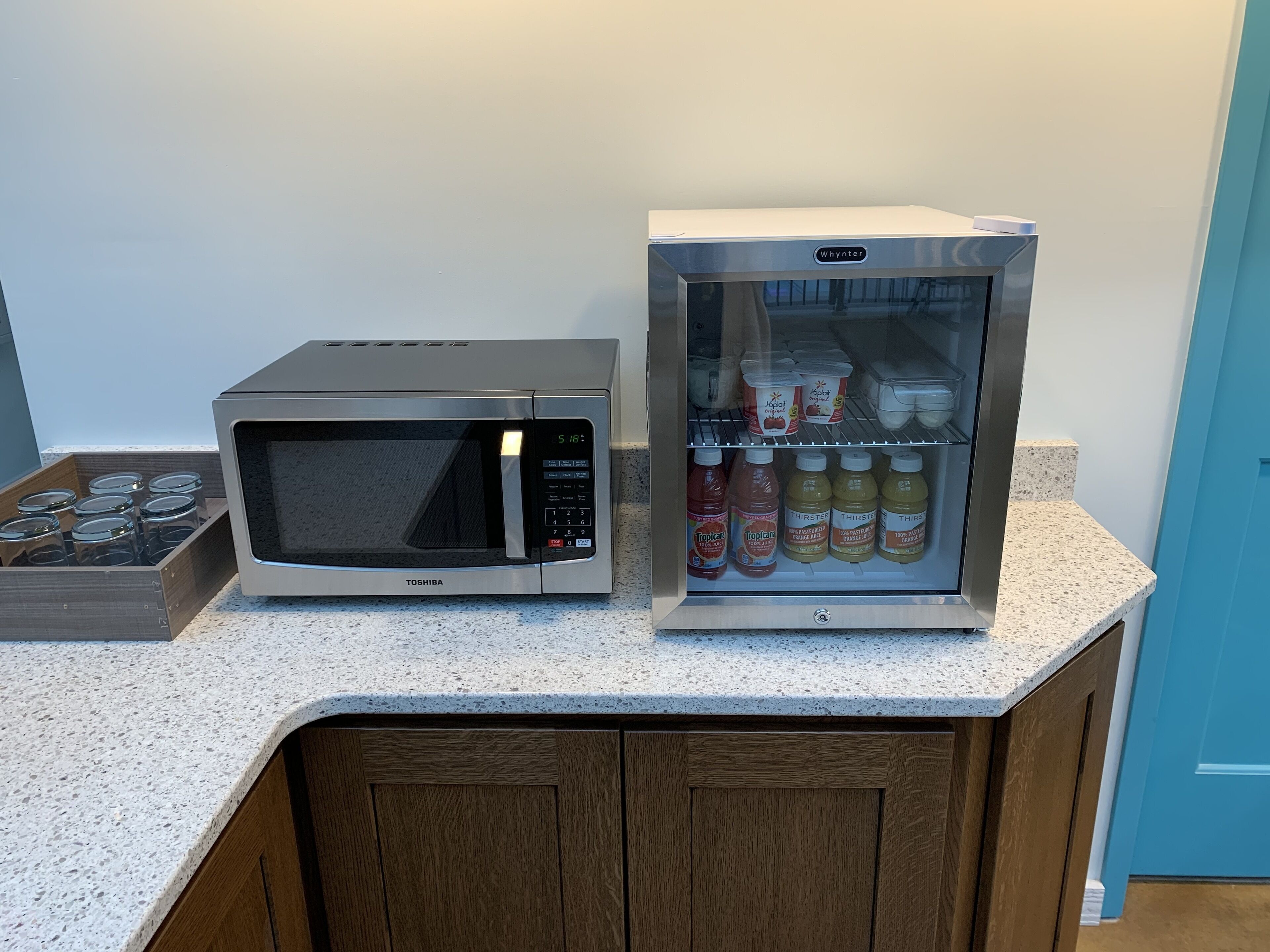 Cocina con microondas y refrigerador que contiene bebidas.