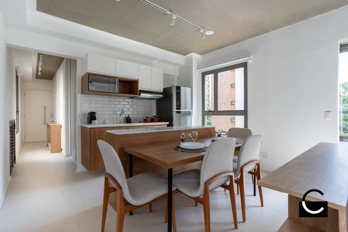 Een moderne keuken met witte kasten, een houten eiland en een eethoek met stoelen.