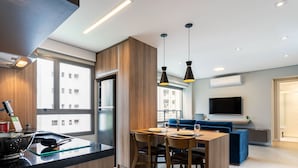 A modern kitchen with a stainless steel refrigerator, a sink with a colander, and a dining area with a table and chairs. -  Charlie Vila Nova Conceição Jacques Félix (São Paulo)