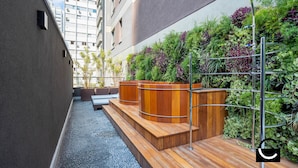 A rooftop terrace with a wooden deck, seating areas, and a vertical garden. -  Charlie Vila Nova Conceição Jacques Félix (São Paulo)