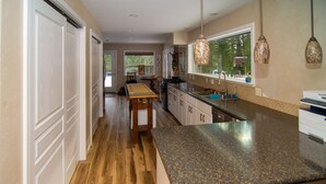 A kitchen with wooden flooring, a granite countertop, and pendant lighting.