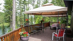 A wooden deck with outdoor furniture, a covered seating area, and potted plants.