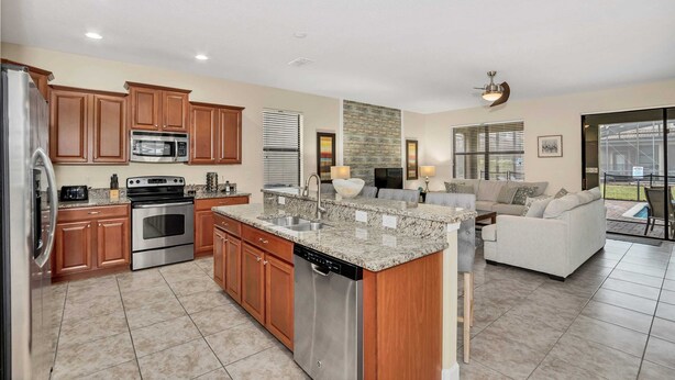 A modern kitchen with stainless steel appliances, wooden cabinets, and a granite countertop. - Modern Home, Big Pool Area Near Disney, CDC Cleaning 4cg456 (Davenport)
