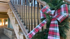 A staircase with a festive garland and plaid bow decoration. - Emma's View On Lay Lake<br>SUMMERTIME ON LAY LAKE IS THE BEST!!☀️ (Shelby)