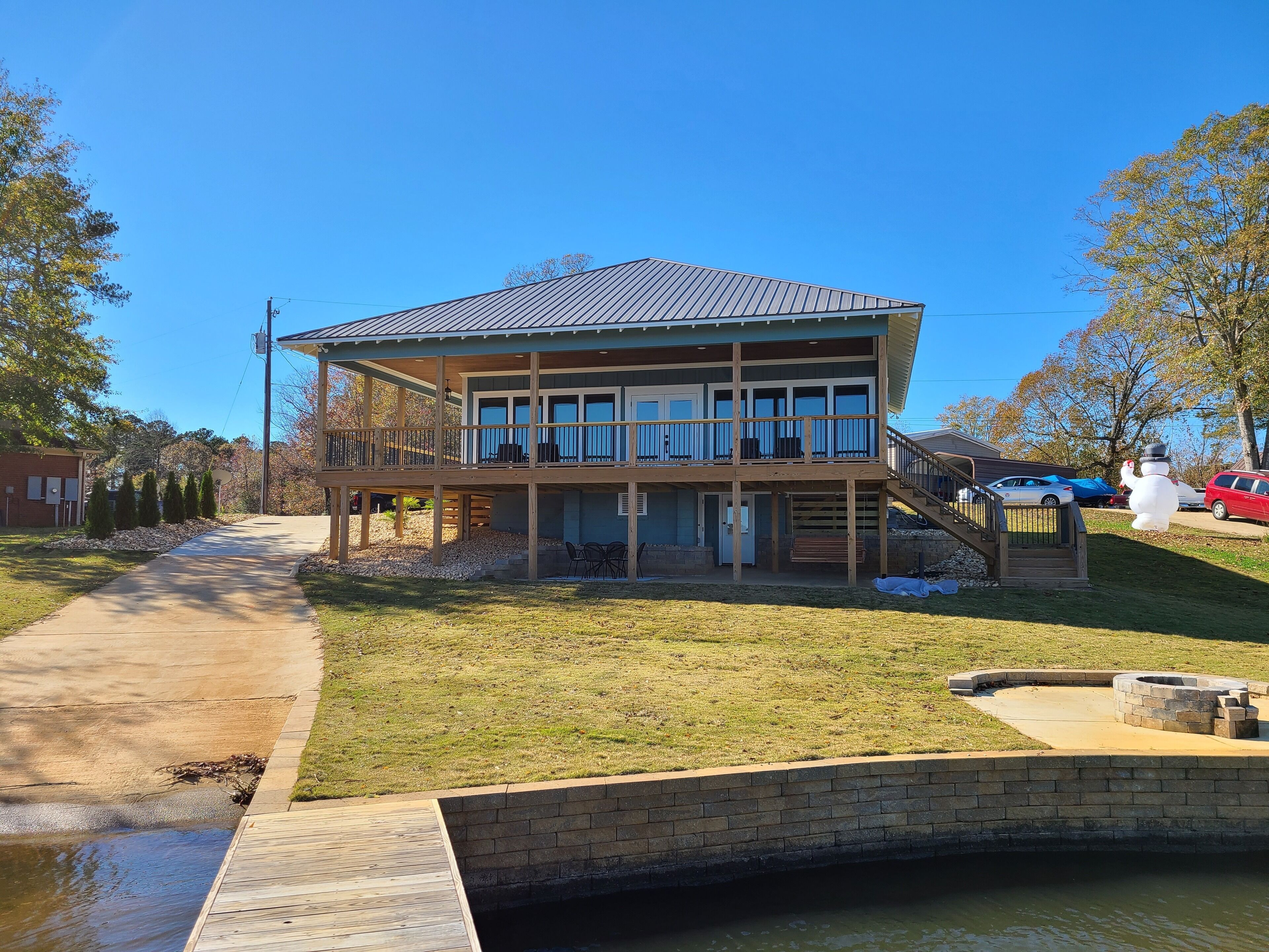 Une maison à deux étages avec une terrasse, une petite piscine et un mur en pierre.