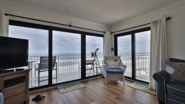 Ein geräumiger Balkon mit Blick auf das Meer, ein Teleskop, ein Stuhl und eine Couch.