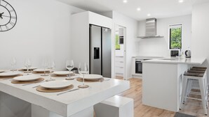 Une cuisine moderne dotée d’un îlot central, de meubles blancs et d’une grande fenêtre.