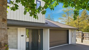 Une maison moderne à deux étages, dotée d’un garage, d’un mur en pierre et d’un arbre au premier plan.