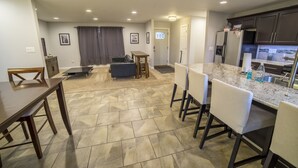 A modern kitchen with a marble countertop, dark wooden cabinets, and a dining area with a table and chairs.