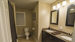 A bathroom with two sinks, a toilet, and a shower.