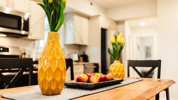 A kitchen with two yellow vases on a table, containing yellow tulips and apples. - The Inn at Newton Highlands, boutique apartment-hotel (Newton)