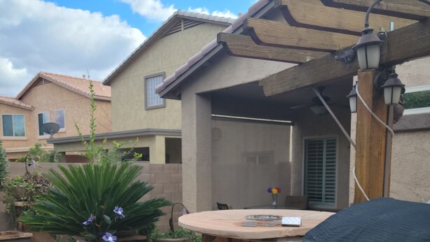 Un patio con una columna de piedra, un espacio de estar cubierto y vista hacia un edificio residencial al fondo.