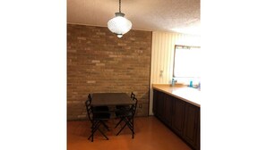 Une cuisine avec un mur en briques, une table à manger avec des chaises et un luminaire suspendu.