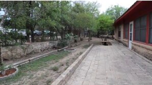 Une cour avec un chemin pavé, des murs en pierre et des arbres.