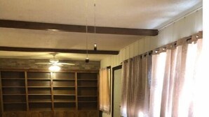 Une pièce spacieuse avec un sol carrelé, un banc en bois le long du mur et un ventilateur de plafond.