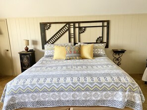 A bed with a patterned bedspread, two bedside tables, and a headboard with a decorative design.