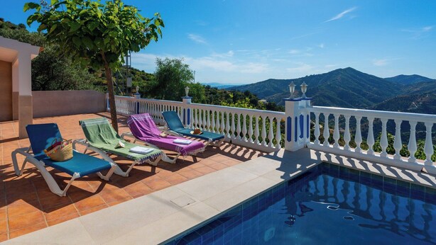 Un espace aménagé au bord de la piscine, avec des chaises longues et une vue sur les montagnes.