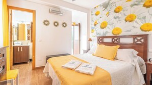 Une chambre d’hôtel comprenant un lit, une table de chevet, un miroir et une porte donnant accès à une salle de bain.