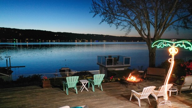 A wooden deck with a hot tub, outdoor seating, and a fire pit. - Erlands Point Beach House (Bremerton)