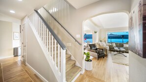 A spacious living area with a staircase, a view of the ocean, and a cozy seating arrangement. - Erlands Point Beach House (Bremerton)