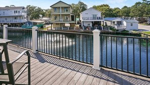 A waterfront property with a wooden deck, a small boat dock, and a building with a balcony. - Site M66 Lakeview 3BR Golf Cart | Walk to Beach/Waterpark | (Myrtle Beach)