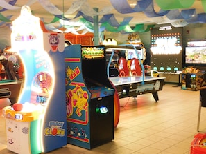 A gaming arcade with various machines, including a pinball table and claw machines.
