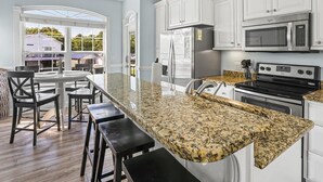 A modern kitchen with granite countertops, stainless steel appliances, and white cabinetry. - Site M66 Lakeview 3BR Golf Cart | Walk to Beach/Waterpark | (Myrtle Beach)