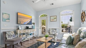 A living room with a sofa, armchair, coffee table, and a bookshelf. - Site M66 Lakeview 3BR Golf Cart | Walk to Beach/Waterpark | (Myrtle Beach)