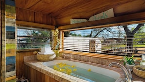 Un intérieur en bois avec une baignoire, une fenêtre avec des stores et une enseigne sur laquelle on peut lire « Alocatura ».