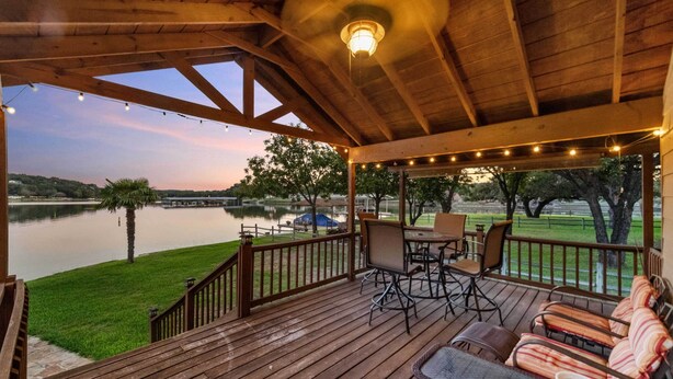 A wooden deck with outdoor furniture, overlooking a lake. - Lakefront Haven ~ 6 Mi to Historic Granbury Square (Granbury)