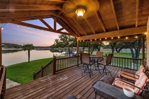 Enjoy a serene lakeside retreat with a deck featuring a table, chairs, and comfortable seating area.